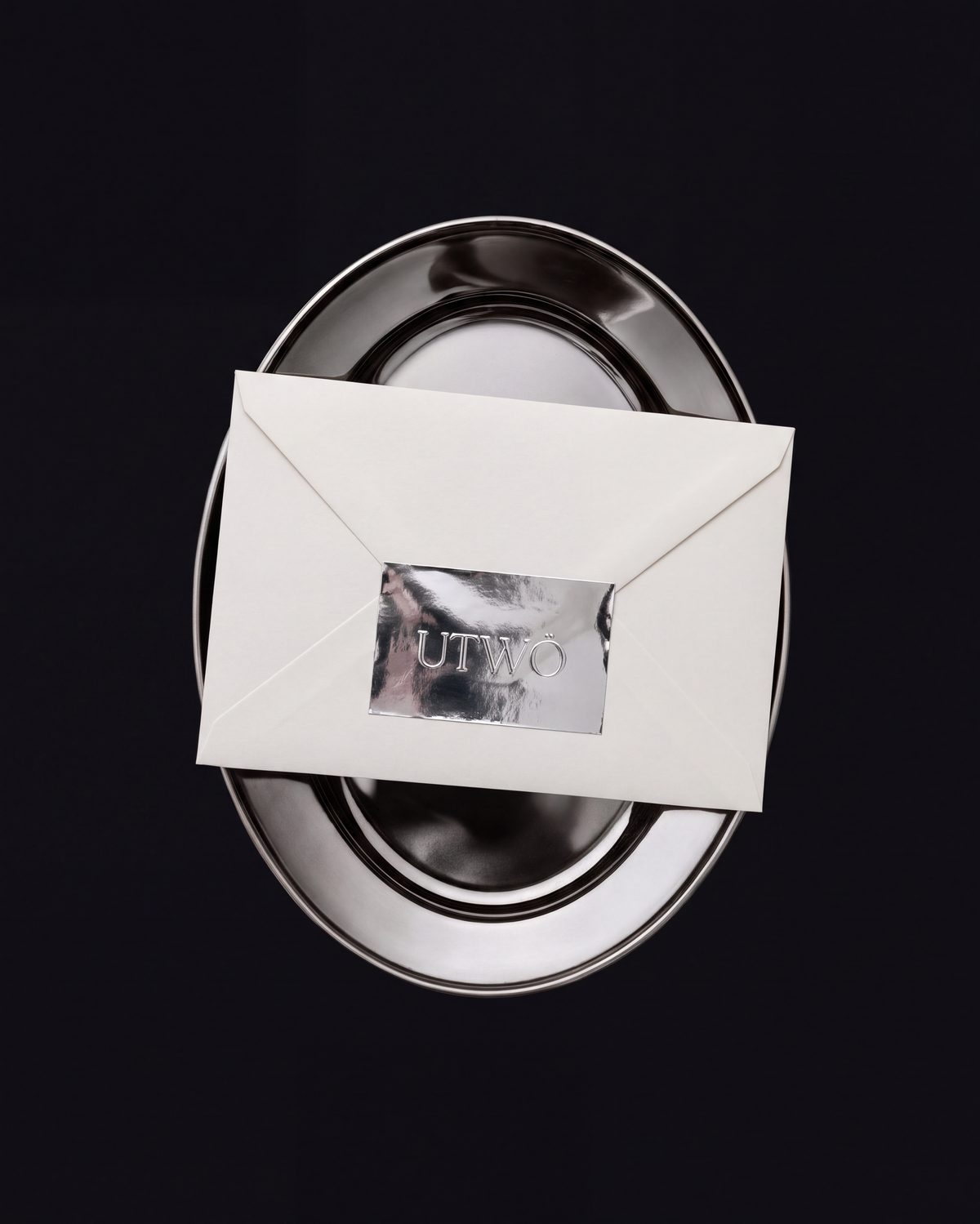 UTWÖ foil-sealed brand envelope on a silver platter, luxury corporate event stationery